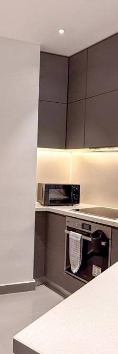 a white kitchen with black cabinets and a white counter top at The 1 -Nicosia Elite Stay- Gym Pool 24h Concierge in Nicosia