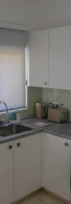 a kitchen with white cabinets and a sink and a microwave at Theo 202 - Cozy 2 Bdr Nicosia Free Parking &amp; Wi-Fi in Nicosia