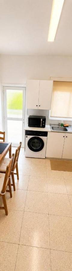 a kitchen with a wooden table and a refrigerator at Theo 302 - Comfort 2 Queen Bdr Nicosia with Parking in Nicosia