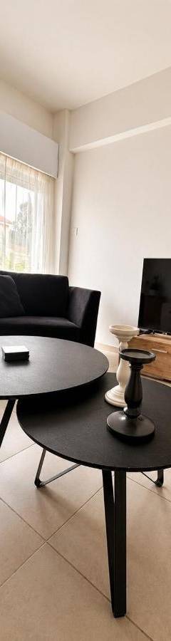 a living room with a table and a couch and a tv at Theo 302 - Comfort 2 Queen Bdr Nicosia with Parking in Nicosia