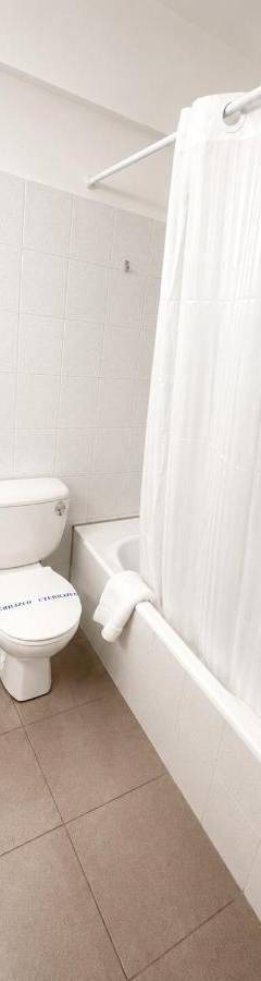 a white bathroom with a toilet and a bath tub at Theo 302 - Comfort 2 Queen Bdr Nicosia with Parking in Nicosia