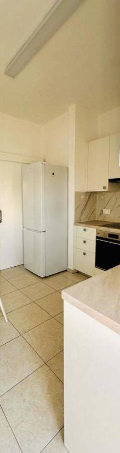a kitchen with a table and a white refrigerator at Theo 403 - Charming 2 Bdr Nicosia, Parking &amp; Wi-Fi in Nicosia
