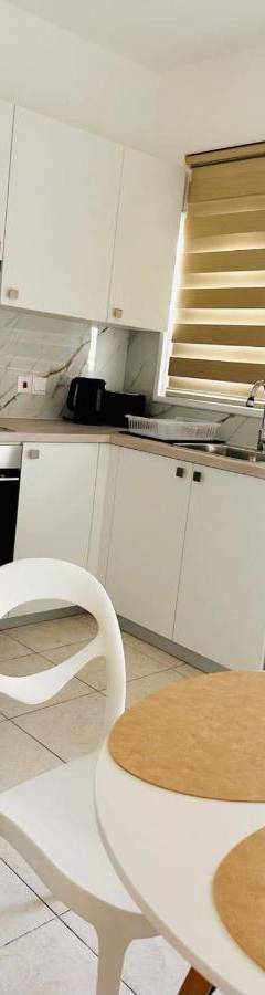 a white kitchen with a table and a washing machine at Theo 403 - Charming 2 Bdr Nicosia, Parking &amp; Wi-Fi in Nicosia