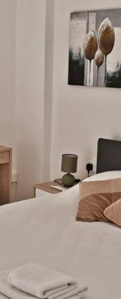 a bedroom with a bed with white sheets and a fireplace at Theo 403 - Charming 2 Bdr Nicosia, Parking &amp; Wi-Fi in Nicosia