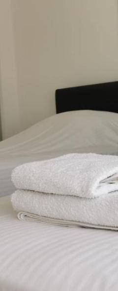 two white towels are stacked on a white bed at Theo 403 - Charming 2 Bdr Nicosia, Parking &amp; Wi-Fi in Nicosia