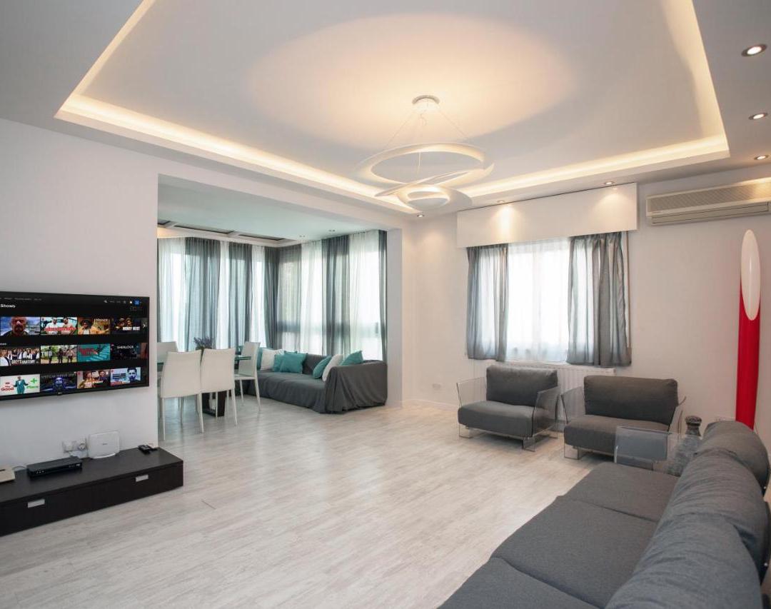 a living room with a couch and a flat screen tv at Mayra Seafront Luxury Apartment (BREAKBOOKING-CY) in Limassol