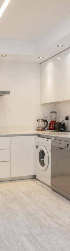 a white kitchen with a sink and a dishwasher at Mayra Seafront Luxury Apartment (BREAKBOOKING-CY) in Limassol