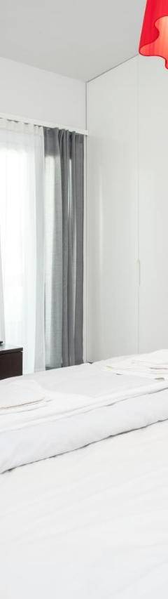 a white bedroom with a bed and a flat screen tv at Mayra Seafront Luxury Apartment (BREAKBOOKING-CY) in Limassol