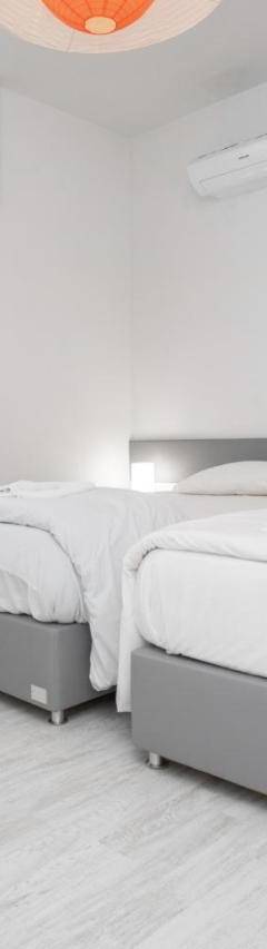 a white bedroom with two beds and a window at Mayra Seafront Luxury Apartment (BREAKBOOKING-CY) in Limassol
