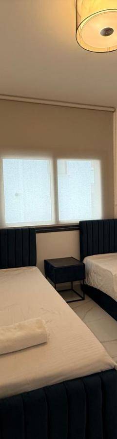 a small room with two beds and a window at Glabur Stays - Nicosia's Finest 2 Bedroom in Nicosia