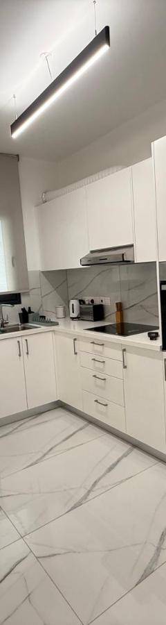 a kitchen with white cabinets and a stainless steel refrigerator at Glabur Stays - Nicosia's Finest 2 Bedroom in Nicosia