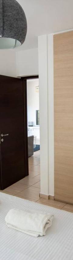 a bedroom with a bed with white sheets and wooden cabinets at Glabur Stays - The Master Atelier - Nicosia City, Free Parking &amp; Wifi, Welcomes You!!! in Nicosia