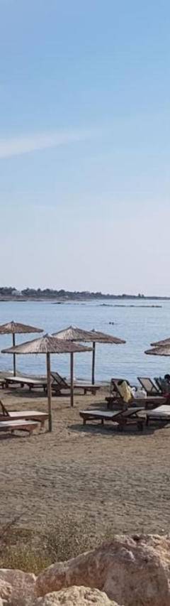 a beach with chairs and umbrellas and the ocean at Glabur Stays! The One -1 - Elite Marina Front! in Zygi