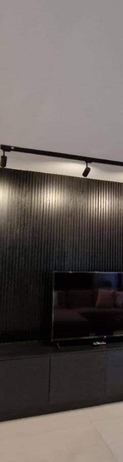 a living room with a tv and a black wall at Raam Luxury Suites in Larnaka