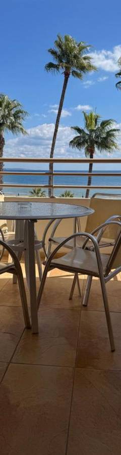 a table and chairs on a balcony with palm trees at Ithaki Phinikoudes Apartment No. 201 in Larnaka