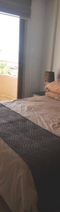 a bedroom with a bed with a view of a balcony at Ithaki Phinikoudes Apartment No. 201 in Larnaka