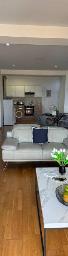 a living room with white couches and a table at Ithaki Phinikoudes Apartment No. 201 in Larnaka