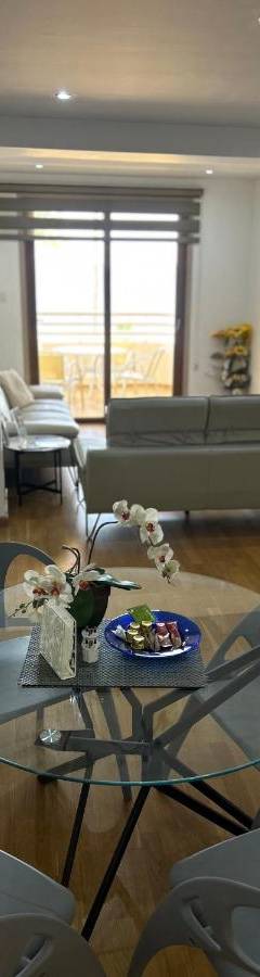 a living room with a glass table and chairs at Ithaki Phinikoudes Apartment No. 201 in Larnaka