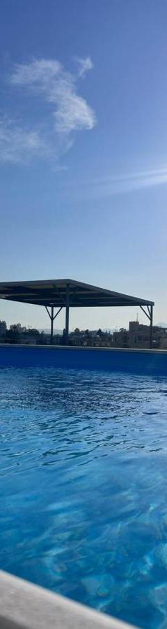 a large swimming pool with the sun in the sky at Alex Residence in Larnaka