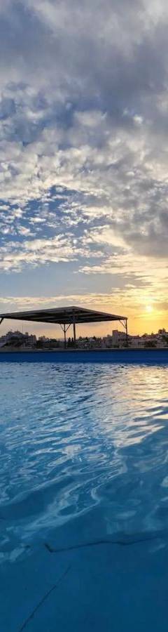 a large swimming pool with a cloudy sky in the background at Alex Residence in Larnaka