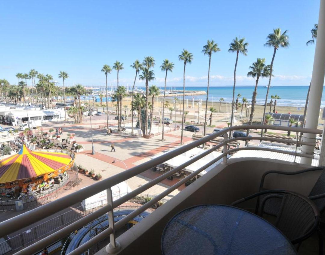 a balcony with a view of the beach and palm trees at Ithaki Phinikoudes Apartment No. 204 in Larnaka