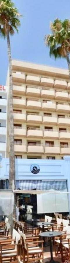 a hotel with chairs and palm trees in front of it at Ithaki Phinikoudes Apartment No. 204 in Larnaka