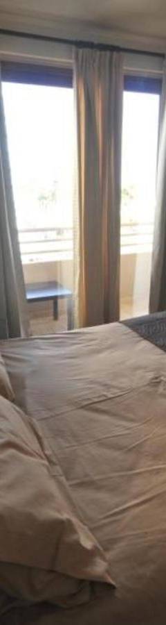 a bedroom with a large white bed with two windows at Ithaki Phinikoudes Apartment No. 105 in Larnaka
