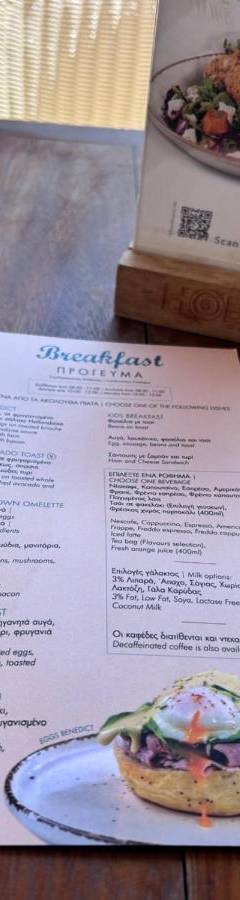 a table with a menu and a plate of food at Ithaki Phinikoudes Apartment No. 105 in Larnaka
