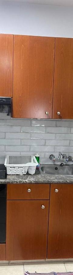 a kitchen with wooden cabinets and a stove and a sink at Alex Beach Apartment 34 in Larnaka