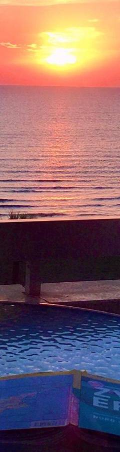 a swimming pool with a sunset over the ocean at Alex Beach Apartment 34 in Larnaka