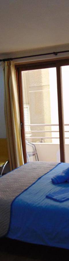 a bedroom with a blue bed and a balcony at Ithaki Phinikoudes Apartment No. 107 in Larnaka