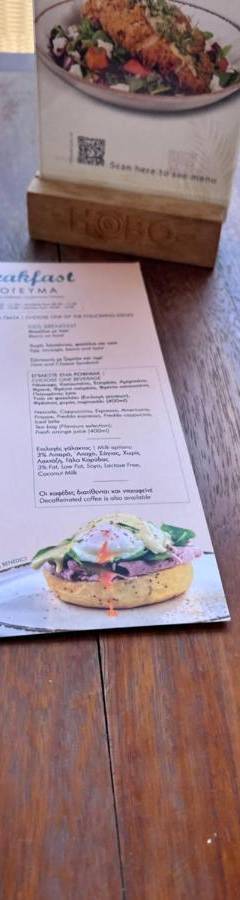a menu on a table with a plate of food at Ithaki Phinikoudes Apartment No. 107 in Larnaka