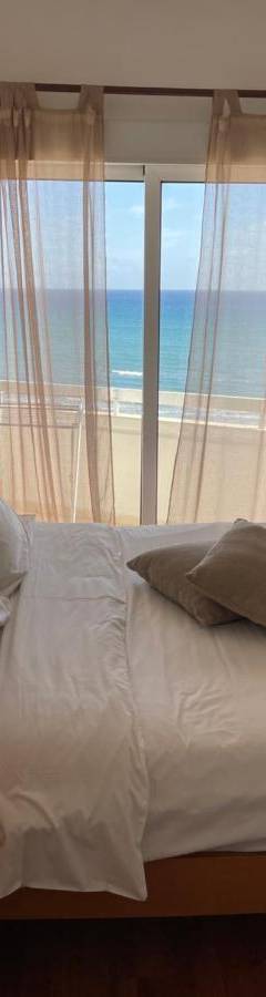 a bedroom with a bed with a view of the ocean at Alex Beach Apartment 51 in Larnaka