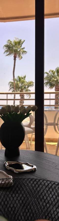 a table with a vase on it with a view of the ocean at Ithaki Phinikoudes Apartment No. 202 in Larnaka