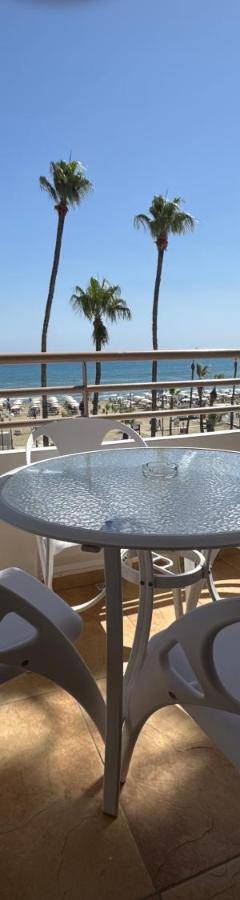 a table and chairs on a balcony with the beach at Ithaki Phinikoudes Apartment No. 202 in Larnaka