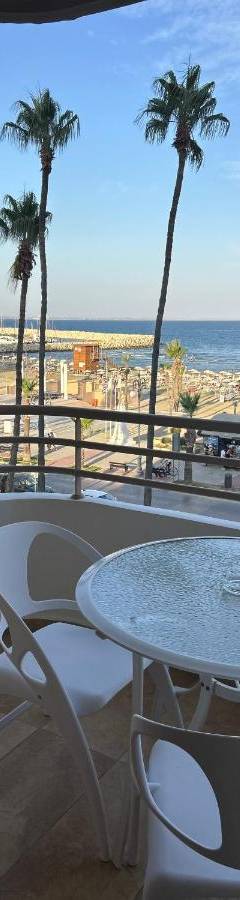 a patio with a table and palm trees and the ocean at Ithaki Phinikoudes Apartment No. 202 in Larnaka