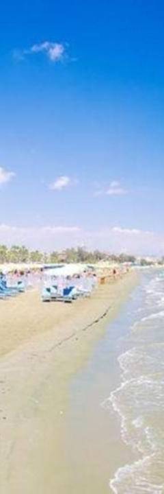 a beach with chairs and umbrellas and the ocean at Ithaki Phinikoudes Apartment No. 207 in Larnaka