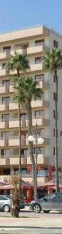 a large building with palm trees in front of it at Ithaki Phinikoudes Apartment No. 207 in Larnaka