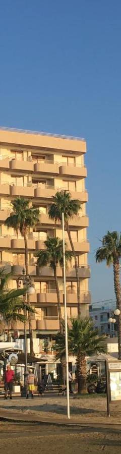 a tall building with palm trees in front of it at Ithaki Phinikoudes Apartment No. 207 in Larnaka