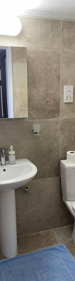 a bathroom with a toilet and a sink and a mirror at Alex Beach Apartment 33 in Larnaka
