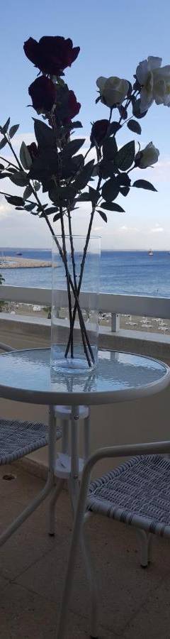 a vase of flowers sitting on a table with a view of the beach at Alex Beach Apartment 33 in Larnaka