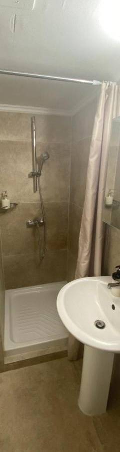 a bathroom with a white sink and a shower at Alex Beach Apartment 33 in Larnaka