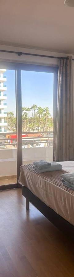 a bedroom with a bed and a large window at Ithaki Phinikoudes Apartment No. 205 in Larnaka