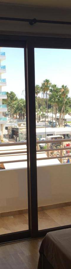 a bedroom with a window with a view of a balcony at Ithaki Phinikoudes Apartment No. 205 in Larnaka