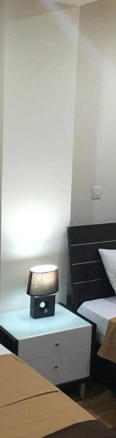 a bedroom with two beds and a night stand with a lamp at Ithaki Phinikoudes Apartment No. 205 in Larnaka