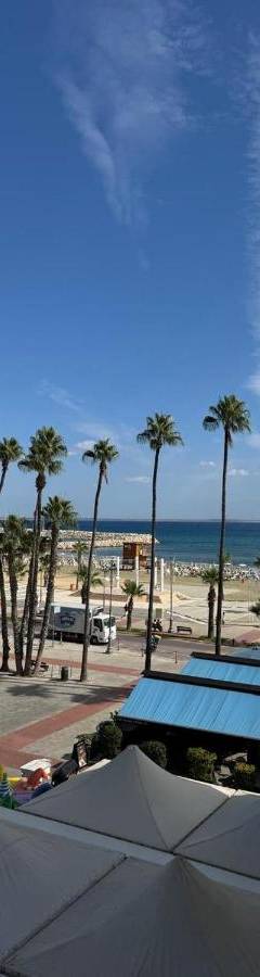 a view of a beach with palm trees and umbrellas at Ithaki Phinikoudes Apartment No. 205 in Larnaka