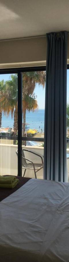a bedroom with a bed and a view of the ocean at Alex Beach Apartment 203 in Larnaka