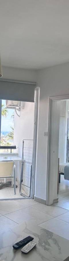 a living room with a couch and a television and a balcony at Alex Beach Apartment 203 in Larnaka