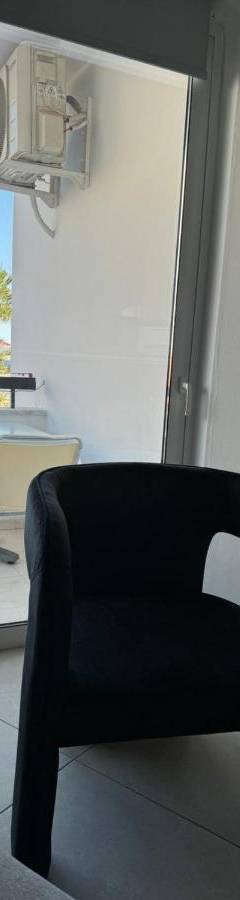 a black chair in a room with a view of the ocean at Alex Beach Apartment 203 in Larnaka