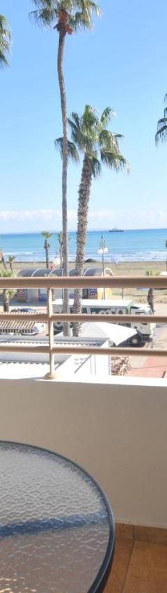 a view of the beach from the balcony of a resort with palm trees at Ithaki Phinikoudes Apartment No. 102 in Larnaka